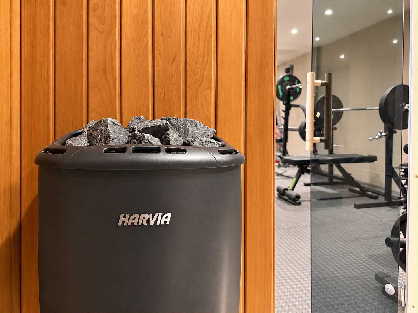 Bastuaggregat i träpanel med gymmet synligt i spegeln